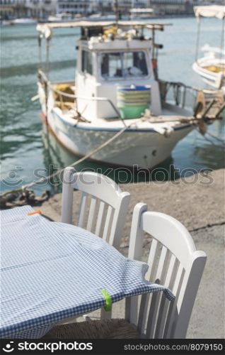 Typical greek restaurant and fish boat on the background. Greece, Gythio