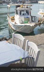 Typical greek restaurant and fish boat on the background. Greece, Gythio