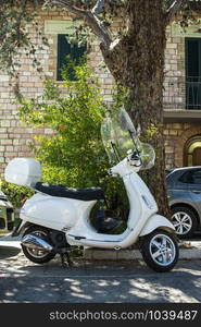 Typical italian motorbike in front of old house facade. Traditional white bike and ancient mediterranean architecture.