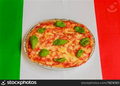 typical italian pizza made of tomato,basil and mozzarella with the italian flag in the background