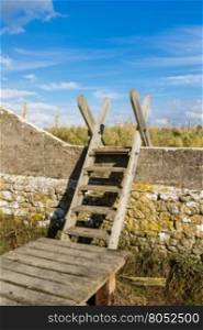 Typical ladder stile, over wall, with bridge over ditch. Aberthaw beach, South Wales, United Kingdom, Europe.