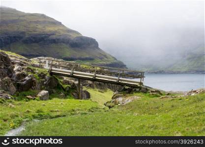 Typical landscape on the Faroe Islands, with green grass, rocks and bridge