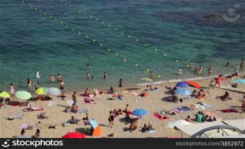 Typical Mediterranean beach in summer day.People on vacation at the beach.Turquoise clear waters during leisure time on the seaside.Holidays scene on the beach.Having sunbath scene.Resting people on sandy beach with pristine and crystal wat