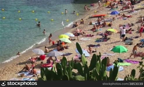 Typical Mediterranean beach in summer day.People on vacation at the beach.Turquoise clear waters during leisure time on the seaside.Holidays scene on the beach.Having sunbath scene.Resting people on sandy beach with pristine and crystal wat