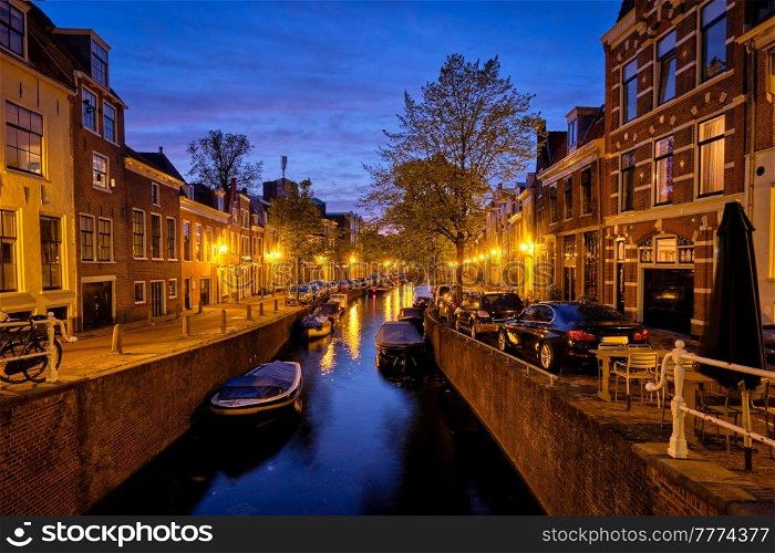 Typical Netherlands view - canal with boats and houses illuminated in the evening. Haarlem, Netherlands. Canal and houses in the evening. Haarlem, Netherlands