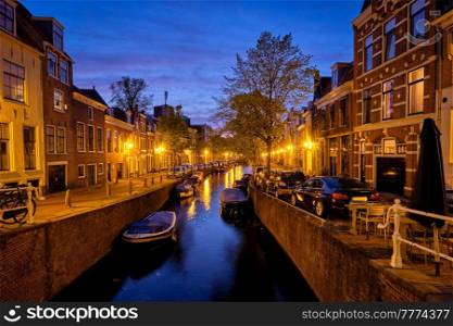 Typical Netherlands view - canal with boats and houses illuminated in the evening. Haarlem, Netherlands. Canal and houses in the evening. Haarlem, Netherlands