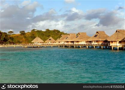 Typical Polynesian landscape - seacoast with palm trees and small houses on water