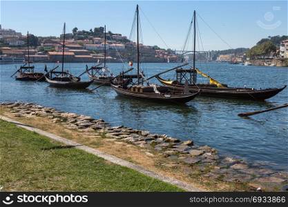 Typical Rabelo Boats on the Bank of the Douro River and Vila Nova de Gaia in background - Porto, Portugal. Typical Rabelo Boats on the Bank of the Douro River - Porto, Por