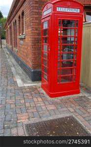 typical red telephone booth and brick wall building on the background