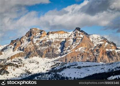 typical rugged orange-yellow mountain formations of the Italian Dolomites in South Tyrol with snow under an cloudy blue sky . typical mountain formations of the Italian Dolomites