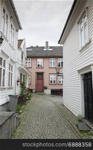 typical street in Bergen in Norway with white wooden houses and flowers at the street