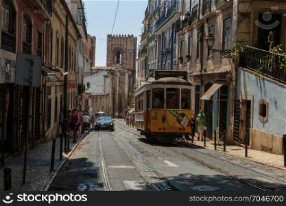 Typical Yellow Vintage Tram in Narrow Street of Lisbon, Portugal