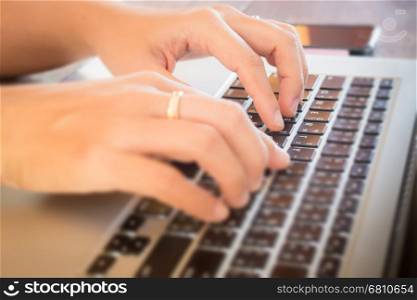Typing on keyboard laptop at work table, stock photo