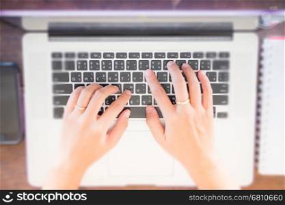 Typing on keyboard laptop top view of wooden table, stock photo