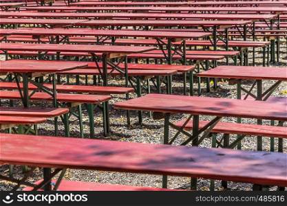 Ugly old red wooden benches and tables, from which the paint peels off, in a beer garden in Hannover