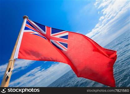 UK ensign british maritime flag of yacht sailboat. blue sky and sea in background. Sailing yachting. Luxury tourism travel.