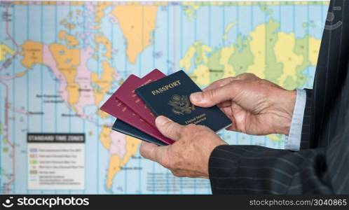 UK or US Citizen with passports and world map of timezones. Senior executive hand holding USA and UK passports against blurred background of world map of timezones. UK or US Citizen with passports and world map of timezones