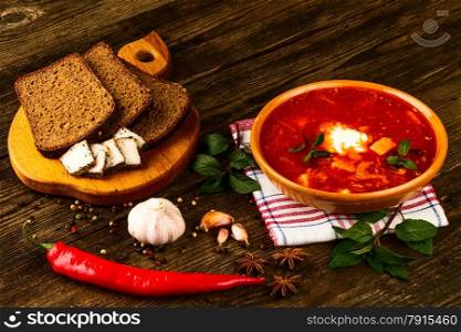 ukrainian borsch with chili pepper and garlic on wooden background
