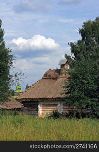 Ukrainian old historical farmhouse and church behind