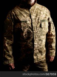 Ukrainian soldier dressed in uniform stands in the dark, low key