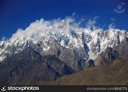 Ultar Sar mountain peak behind the clouds. Batura Muztagh, Karakoram range. Hunza valley, Gilgit Baltistan Pakistan.