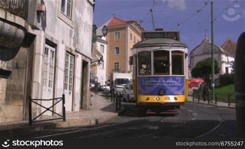 Um die Kurve bergabfahrende blau-gelbe Tram in Lissabon;dahinter fahren Autos unnd LieferwSgen.