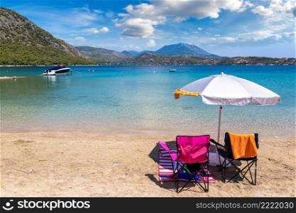 Umbrella and sundecks on sandy beach near Loutraki in a summer day, Greece