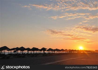Umbrella on sandy sea beach at sunset stock photo