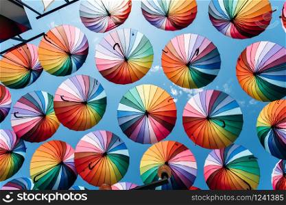 Umbrellas in rainbow color on blue sky background