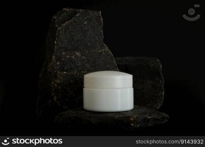 Unbranded natural cosmetic cream packaging standing on stone podium. Cream presentation on the black background. Mockup. Trending concept in natural materials. Natural cosmetic, skincare. Unbranded natural cosmetic cream packaging standing on stone podium. Cream presentation on the black background. Mockup. Trending concept in natural materials. Natural cosmetic, skincare.
