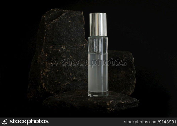 Unbranded natural cosmetic serum packaging standing on stone podium. Serum presentation on the black background. Mockup. Trending concept in natural materials. Natural cosmetic, skincare. Unbranded natural cosmetic serum packaging standing on stone podium. Serum presentation on the black background. Mockup. Trending concept in natural materials. Natural cosmetic, skincare.