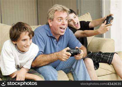 Uncle and his two nephews playing video games together. Could also be father and sons.