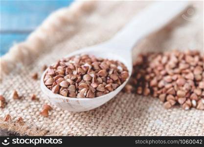Uncooked buckwheat in a spoon on burlap background. Buckwheat is used for cooking. Close-up.. Uncooked buckwheat in a spoon on burlap background. Buckwheat is used for cooking.