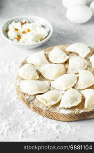 uncooked cottage cheese dumplings on a board with flour