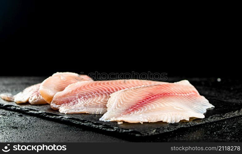 Uncooked fish fillet on the table. On a black background. High quality photo. Uncooked fish fillet on the table.