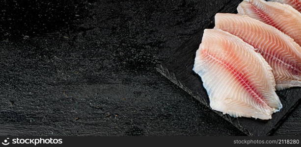 Uncooked fish fillet on the table. On a black background. High quality photo. Uncooked fish fillet on the table.