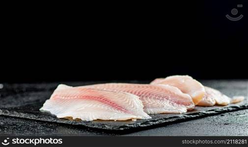 Uncooked fish fillet on the table. On a black background. High quality photo. Uncooked fish fillet on the table.