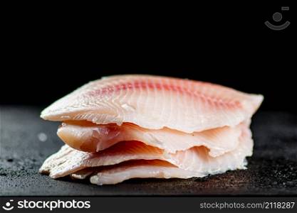 Uncooked fish fillet on the table. On a black background. High quality photo. Uncooked fish fillet on the table.