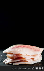 Uncooked fish fillet on the table. On a black background. High quality photo. Uncooked fish fillet on the table.