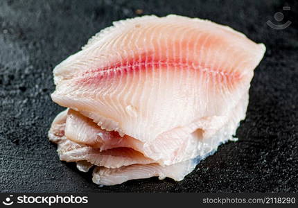 Uncooked fish fillet on the table. On a black background. High quality photo. Uncooked fish fillet on the table.