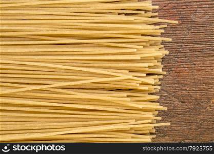 uncooked gluten free, brown rice pasta, spaghetti style on a rustic wood table