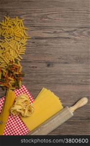 Uncooked italian pasta, brown wood table background