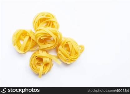 Uncooked Italian pasta tagliatelle nest on white background. Copy space
