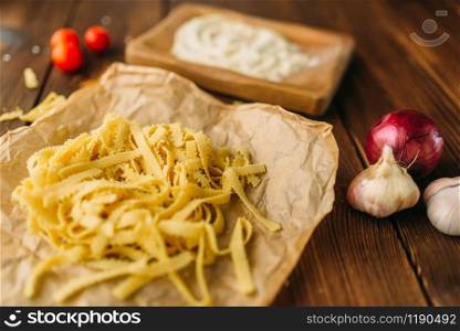 Uncooked pasta on wooden table closeup, nobody. Garnish for stek, herb and garlic, food preparation