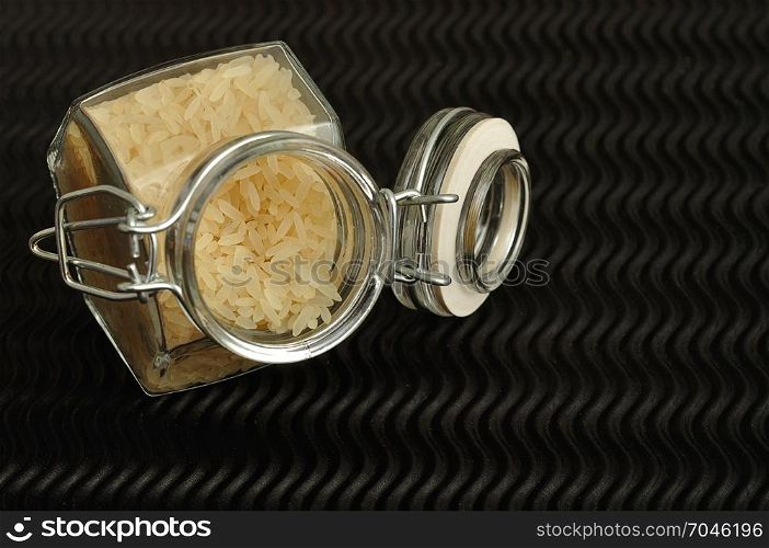 Uncooked rice in a jar displayed on a black background.