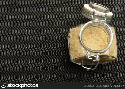 Uncooked rice in a jar displayed on a black background.