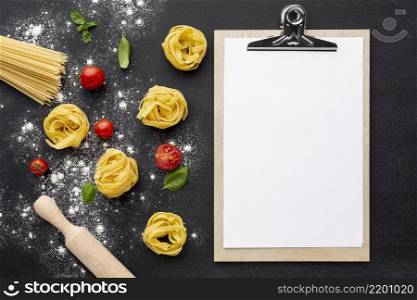 uncooked tagliatelle spaghetti black background with tomatoes rolling pin clipboard mock up