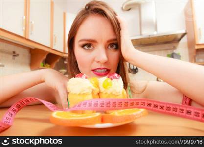 Undecided woman looking at delicious cake with sweet cream and fruits on top. Girl with tape measure trying to resist temptation. Slimming diet dilemma.. Woman with tape measure and cake. Diet dilemma.