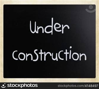 ""Under construction" handwritten with white chalk on a blackboard"