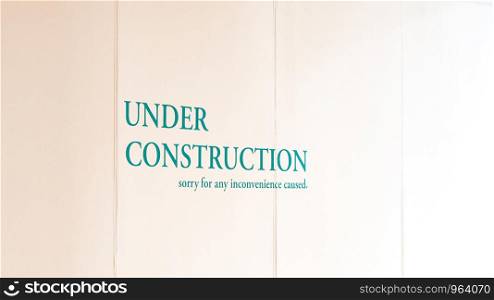Under construction warning sign painted over wooden board in luxury department store.